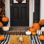 DIY Halloween doormat with 'Spooky Season' ghost design layered on black-and-white checkered mat, surrounded by pumpkins and fall decorations.